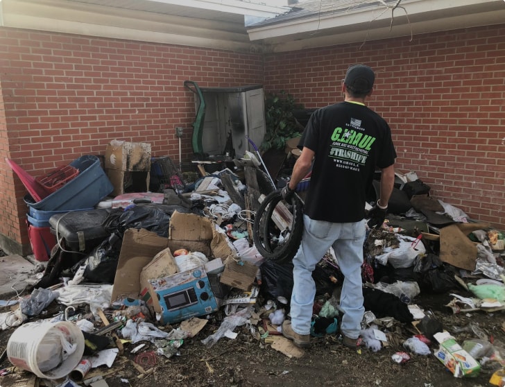 employee staring at a pile of trash in yard